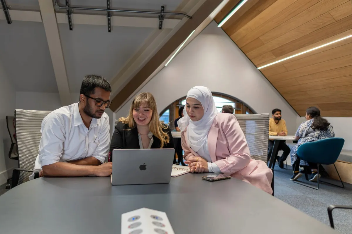 A group of students working in front of a laptop at Leeds City Campus.