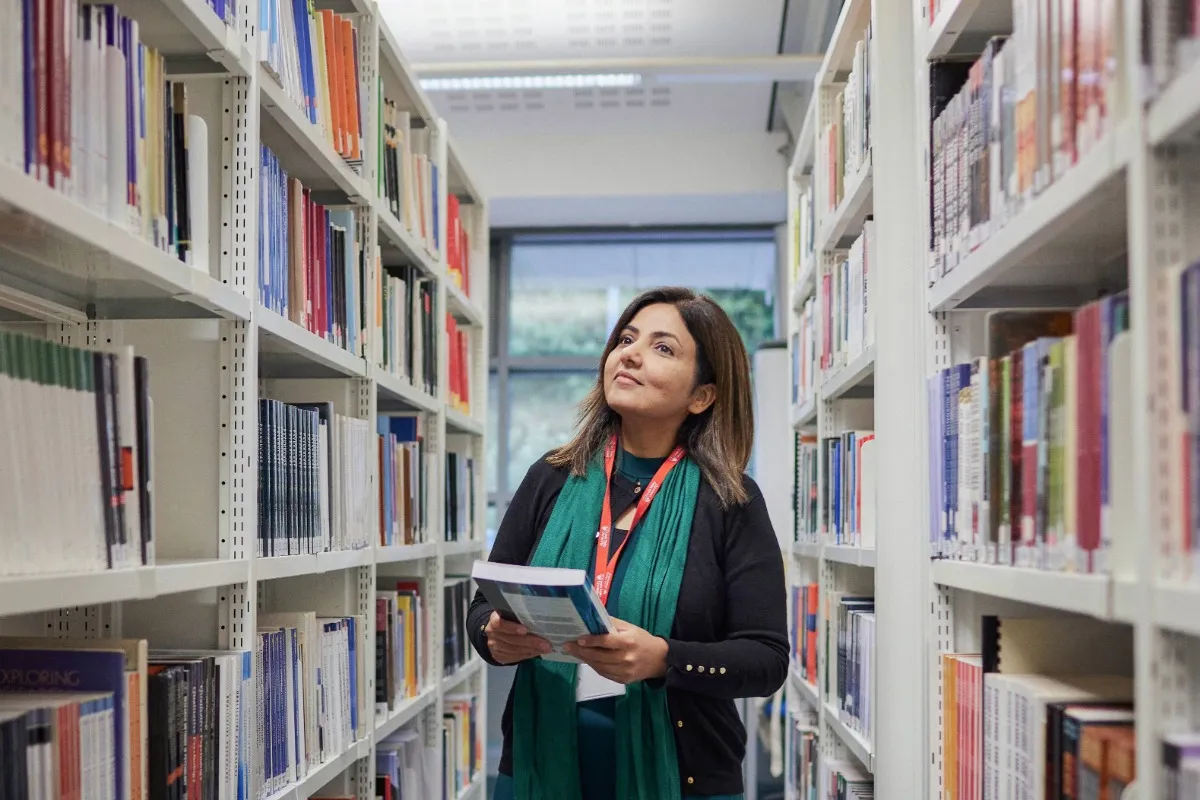 Student in the Main Campus library looking through books.