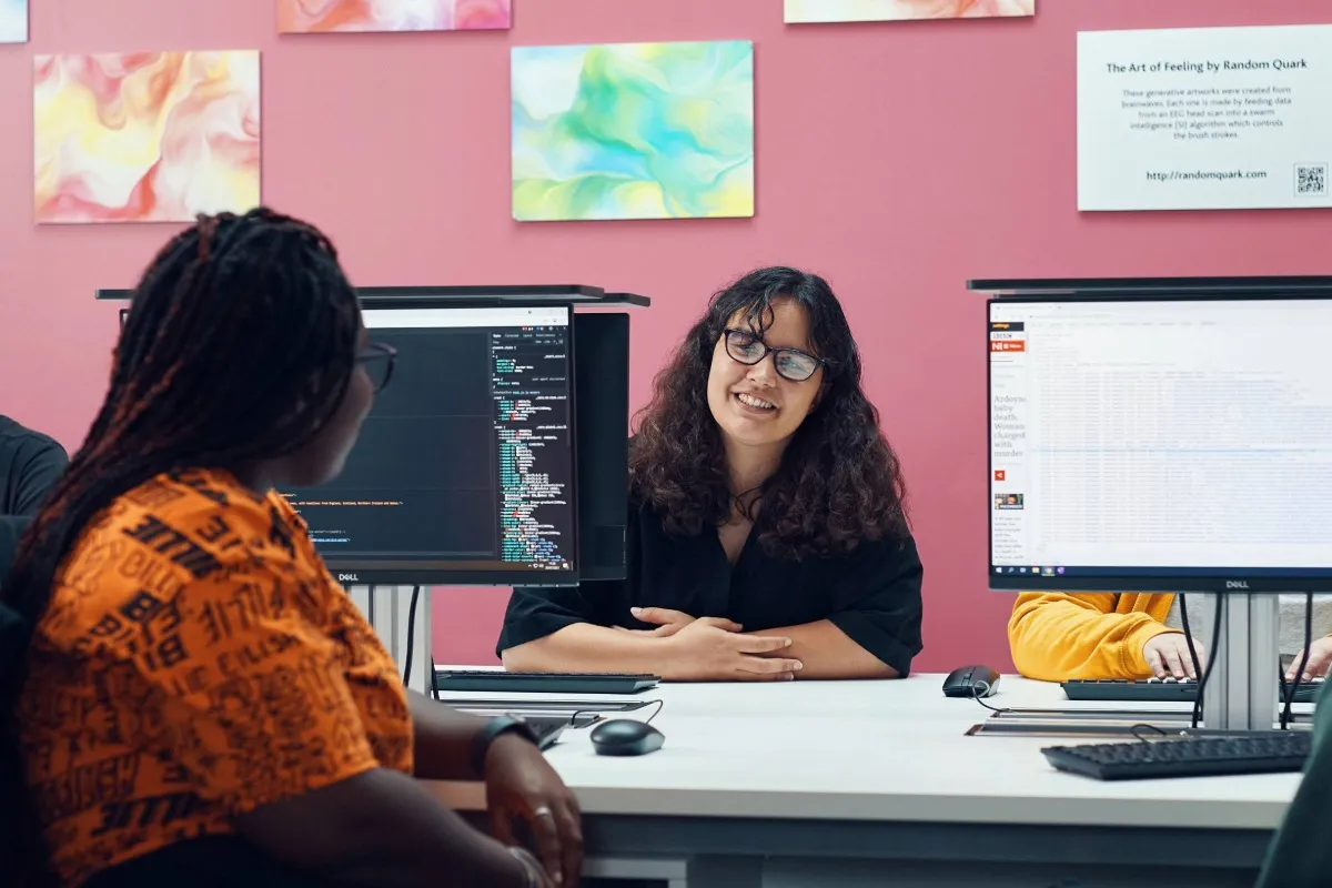 Two students working on a computer and socialising in a classroom at Main Campus.
