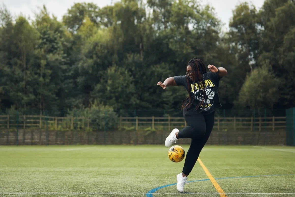 Student playing football on the outdoor pitch at Main Campus.
