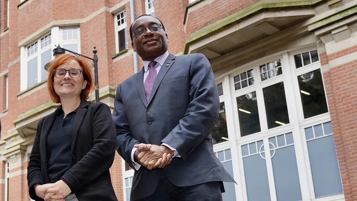 A man and a woman posing outside Leeds Trinity University City Campus..