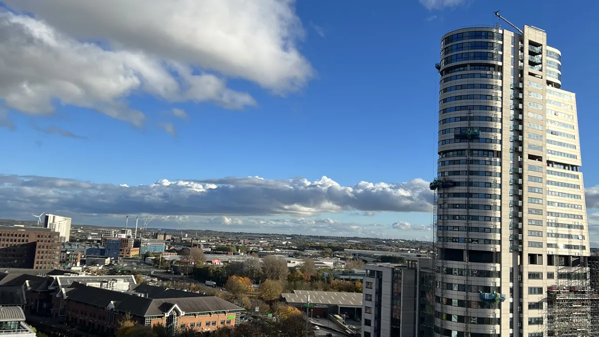 A photo of Leeds from a high point with a large glass building on the right overseeing the city..