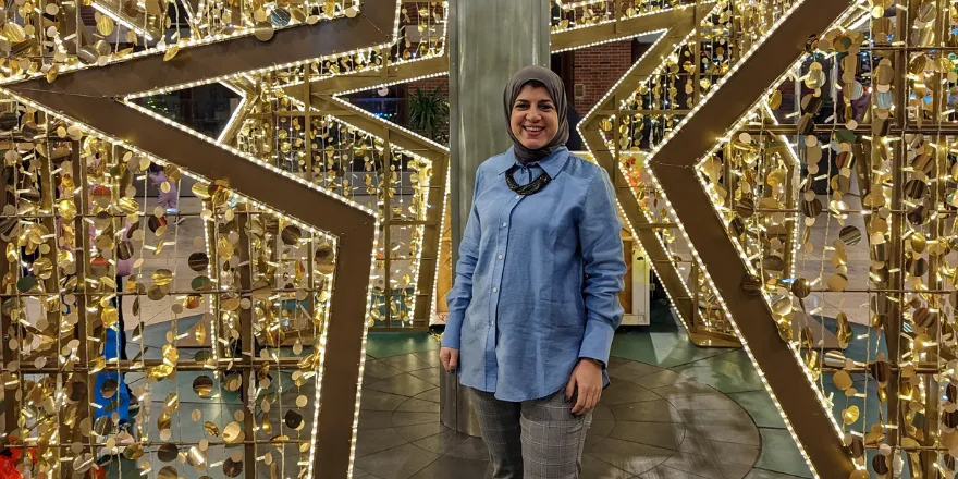 Female member of staff stood by art installation.