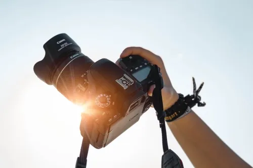 Hand holding camera up to sun .