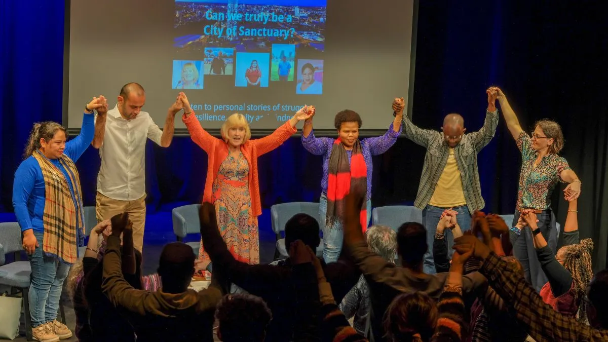 A group of people with join hands and raise their arms.