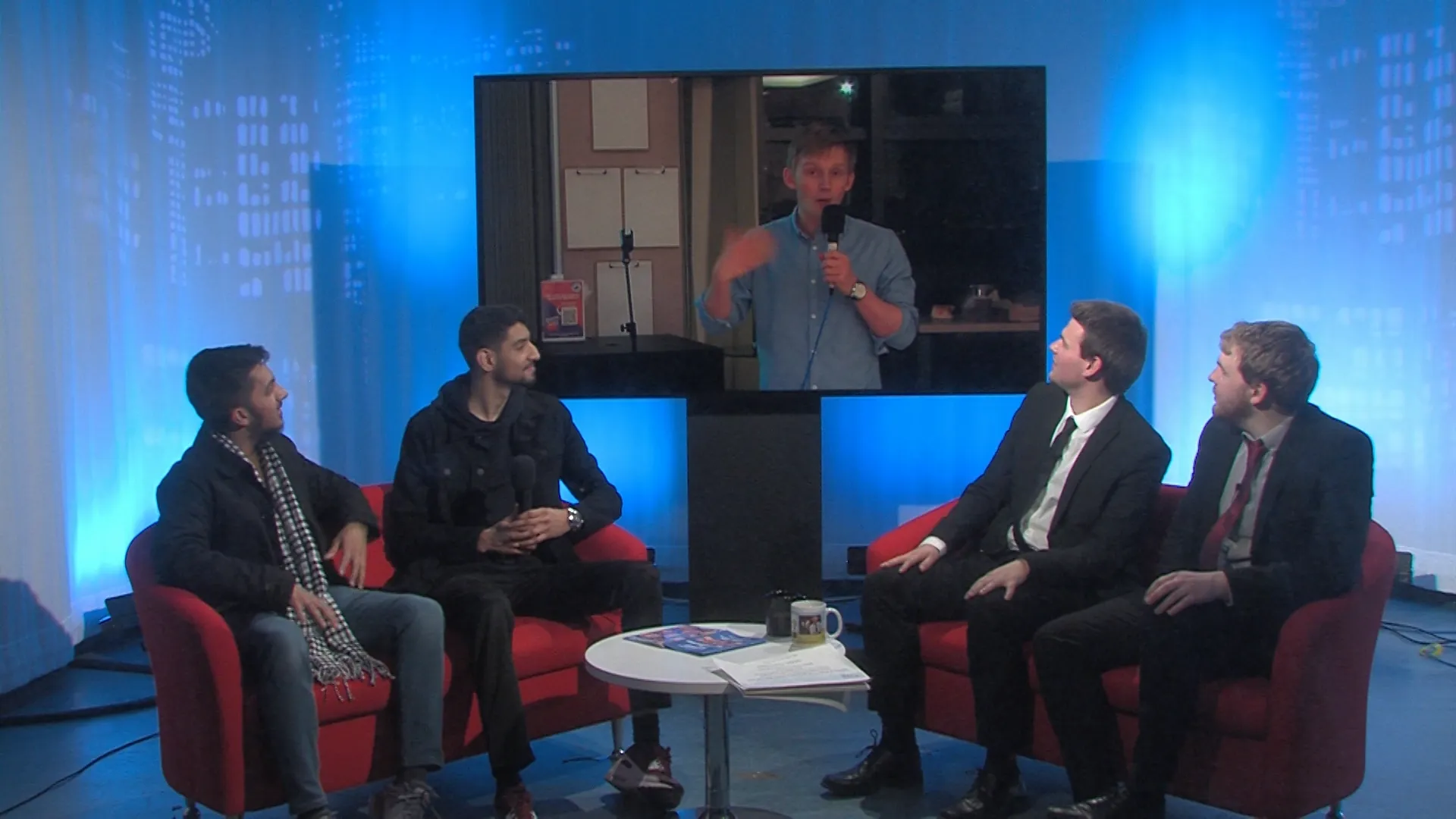Hosts, interviewees and live feed in tv studio.