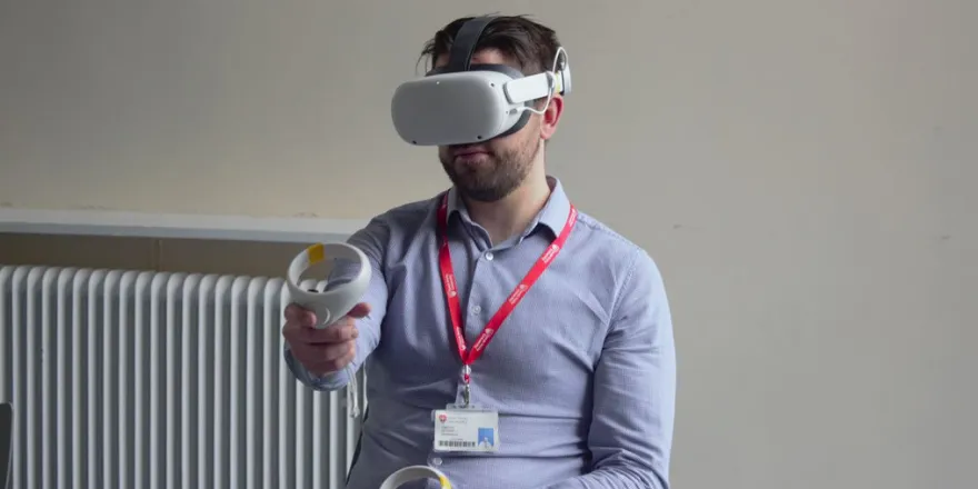 Male sits with Virtual Reality headset on.