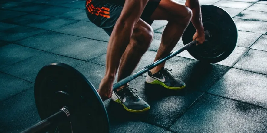 Man squats with weighted barbell.