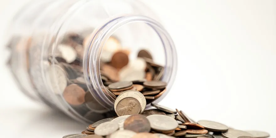 Coins spilling out of a glass jar.