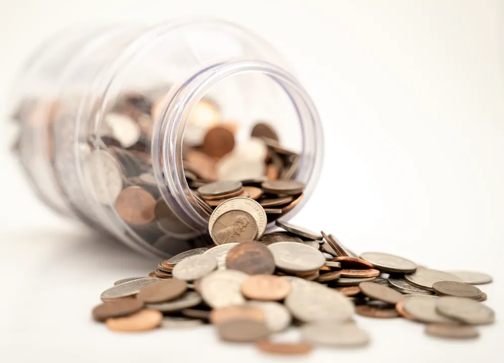 Coins spilling out of a glass jar.