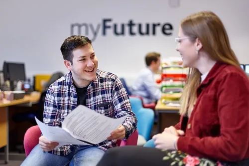 Male and female student in myFuture office discussing opportunities .