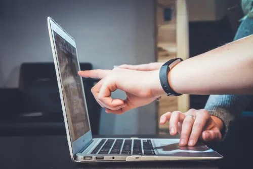 Hand pointing at laptop.