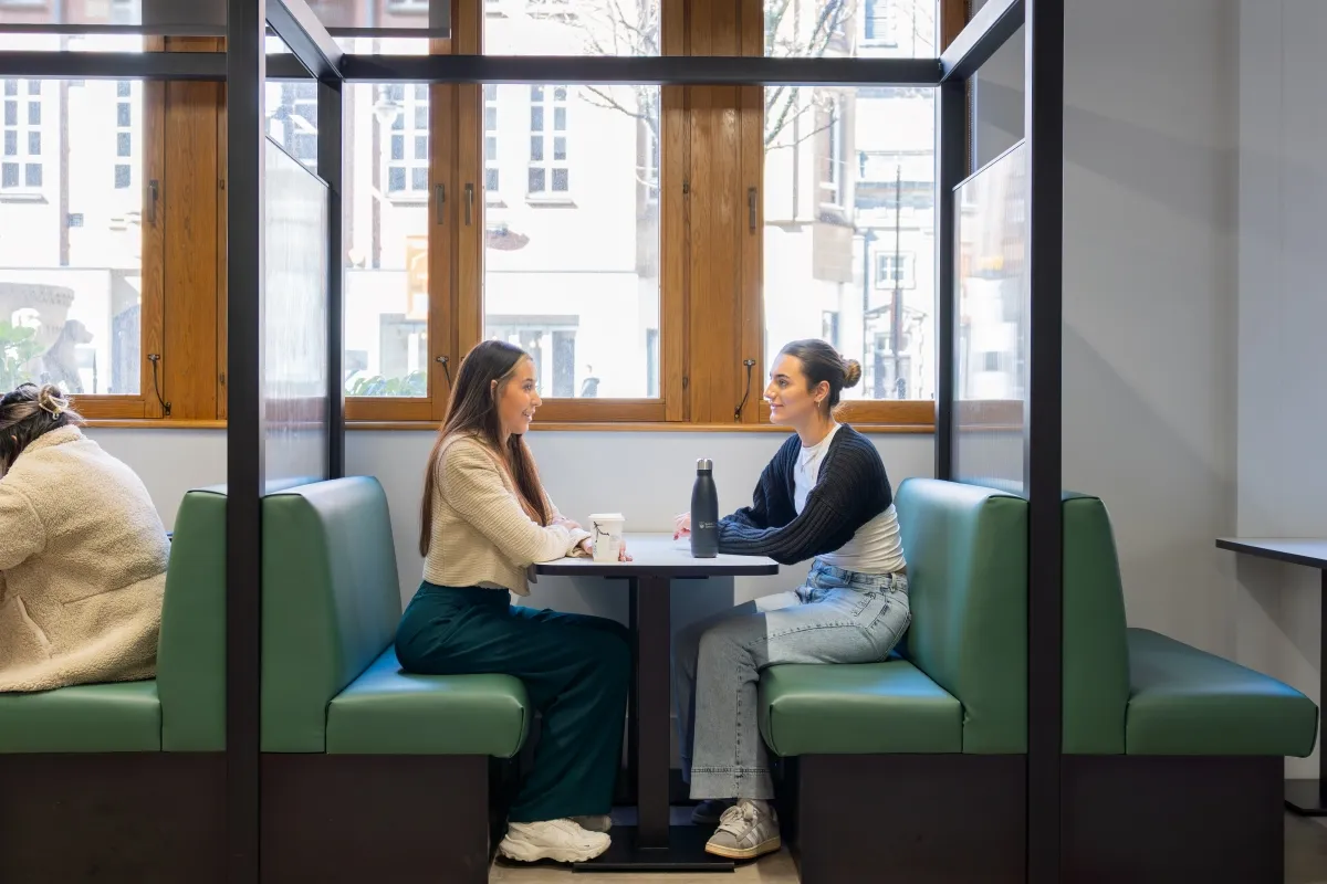 Two students sat at a booth in the Leeds City Campus Cafe..
