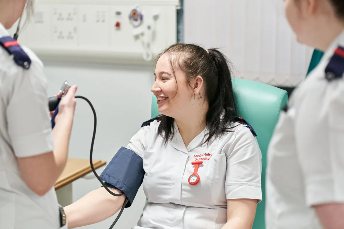Nursing students at Leeds Trinity University practising blood pressure checks in a clinical skills room.