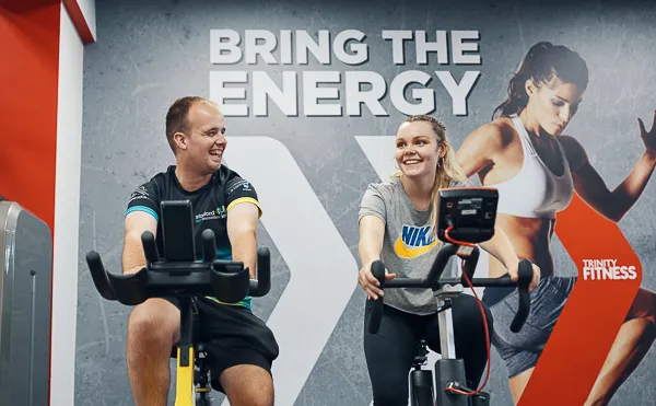 Male and female students using exercise bikes in Trinity Fitness.