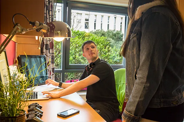 Two students talking in All Saints Court.