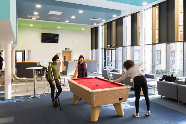 three students playing pool.