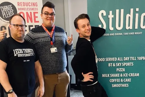 Brett, Connor and Christopher posing in front of a sign for the StUdio Bar area.