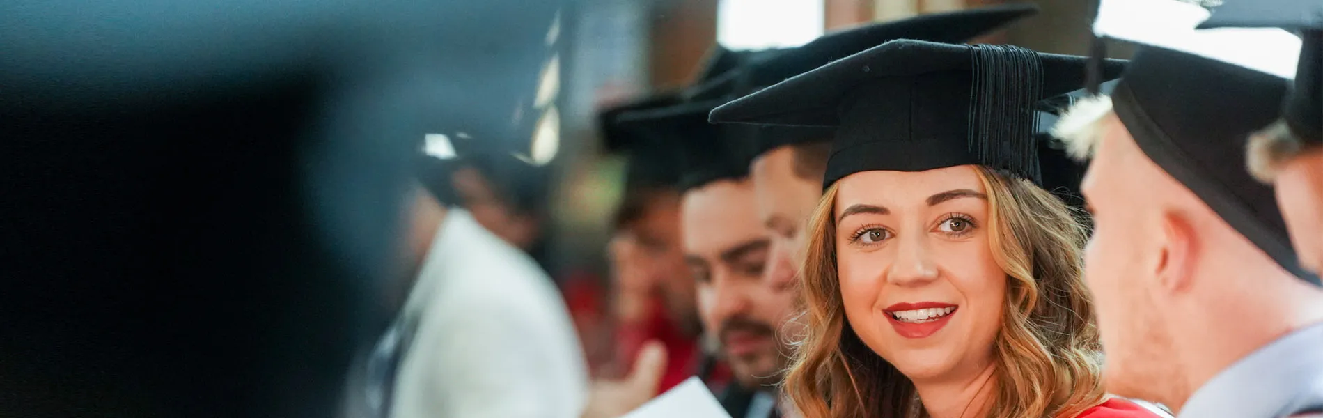 Close-up photo of a graduate smiling during their graduation ceremony.