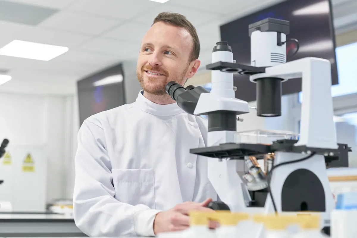 Biomedical Science lecturer working in Biomedical lab using microscope