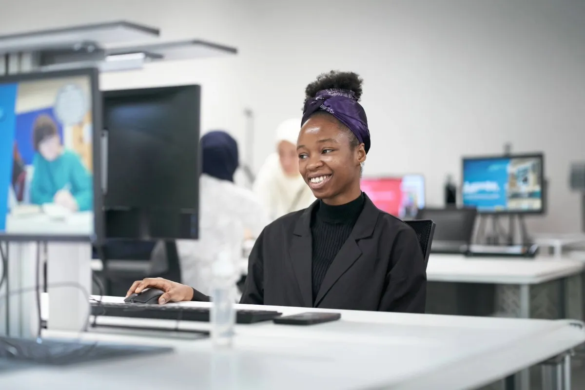 A student smiling whilst using a computer.