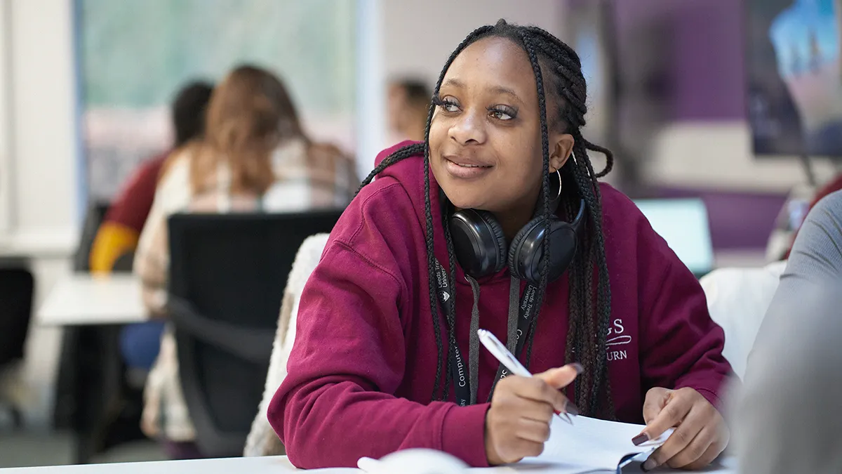 A student in a burgundy hoodie paying attention in classroom..