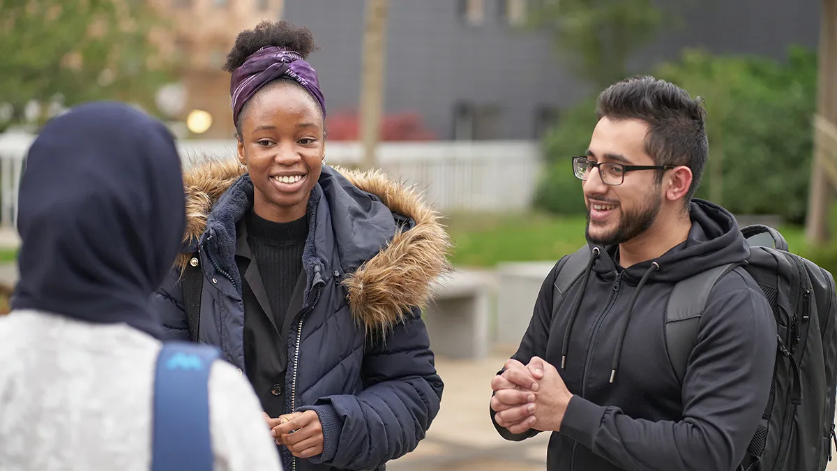 Three students chatting on campus..