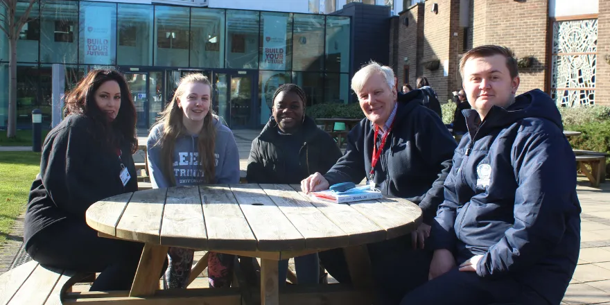 Law students sat with lecturer outside university.