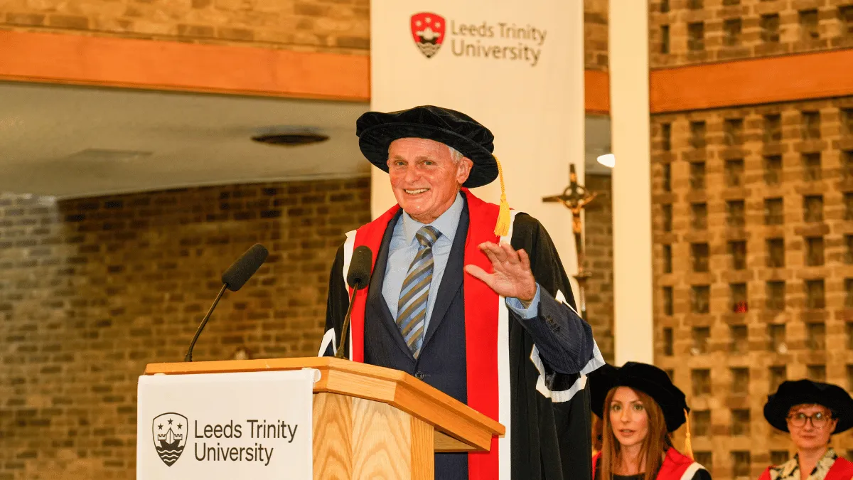 A male academic in cap and gown speaking at Leeds Trinity University..