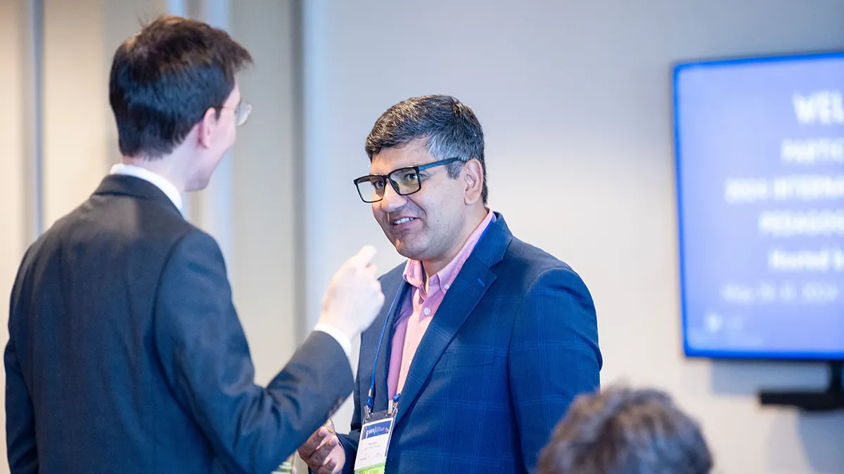An academic speaking to another academic at an event..