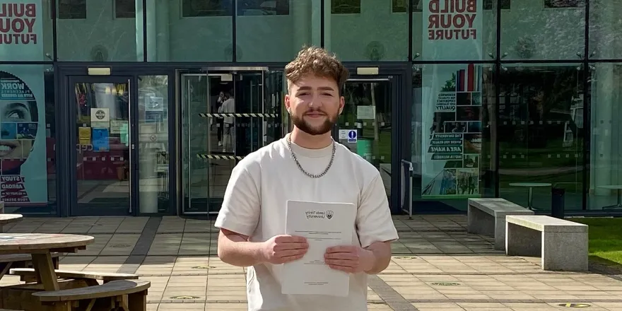 Brunette male in white t-shirt holds white paper.