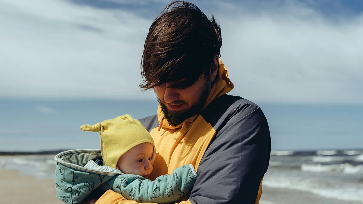 A young dad holding his baby on the beach..