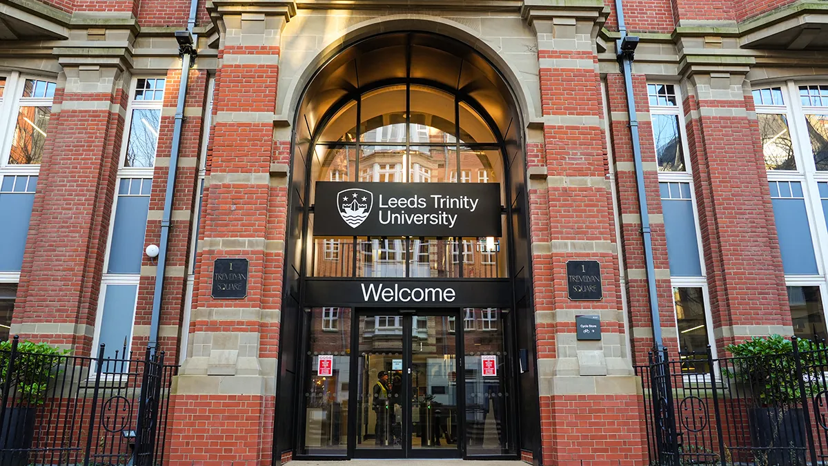 The entrance to the Leeds Trinity University City Campus, a black door on which are printed, in white, the words Leeds Trinity University, welcome..