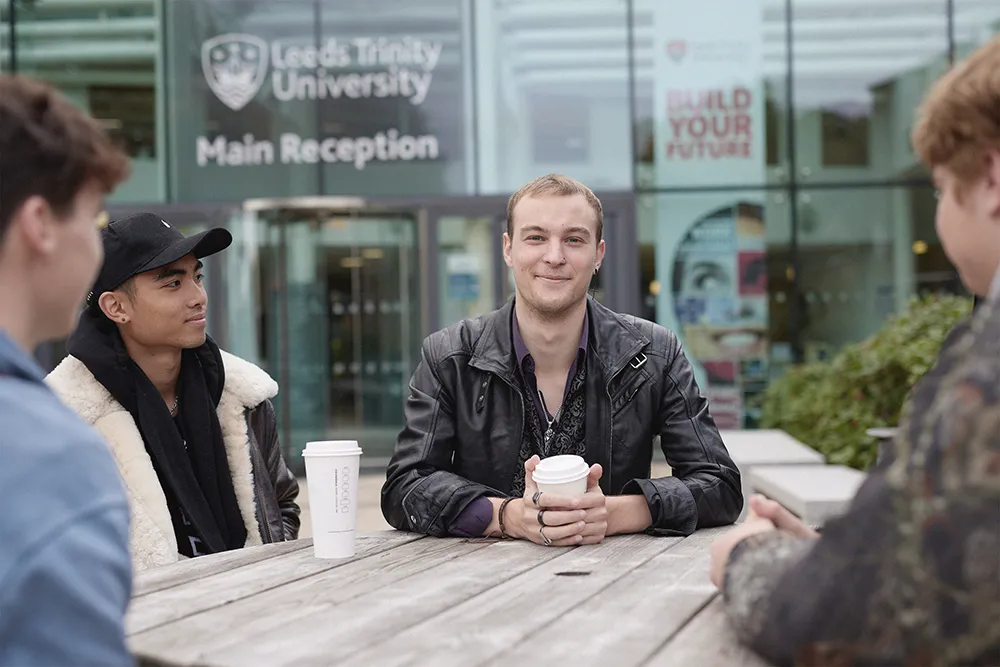 Students sitting on a picnic bench outside the Atrium on Main Campus in Horsforth.