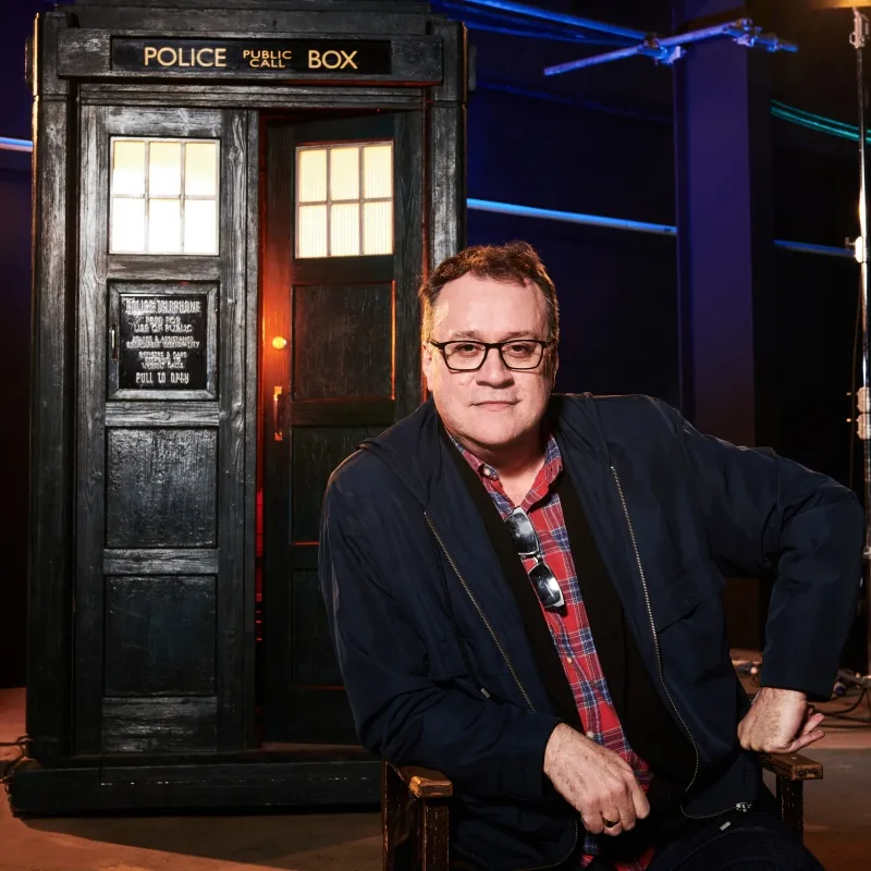 Headshot of Russell T Davis sitting in front of the Tardis..