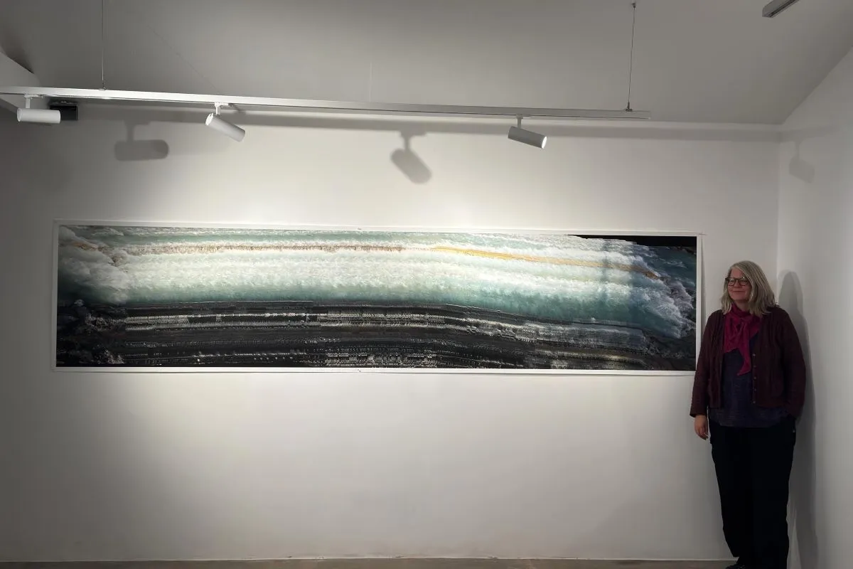 Image of lecturer and exhibitior, Katrin Joost standing next to her photographic work at an external exhibition..