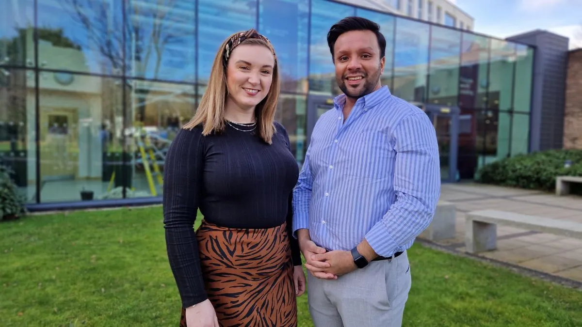 An image of two lecturers in front of the Main Reception at the Main Campus in Horsforth.