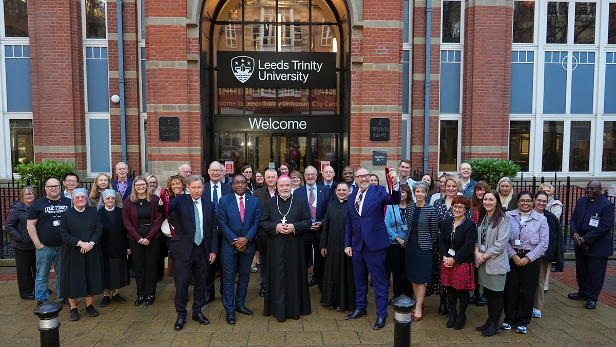 A group of guests with the Bishop of Leeds in front of the Leeds Trinity University City Campus..