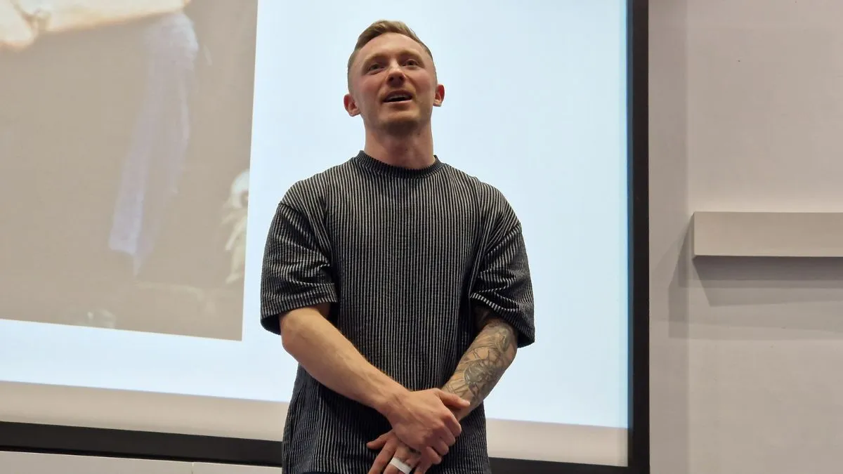 Olympian Nile Wilson stands at the front of an auditorium.