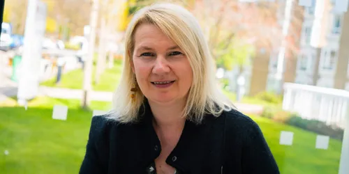 Female with blonde short hair smiles wearing black jacket