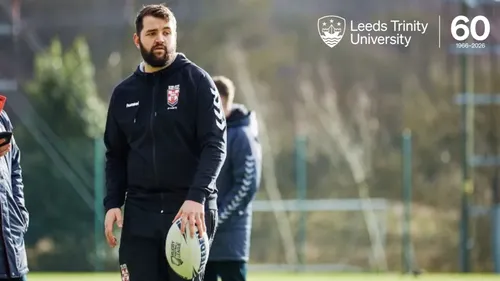 Alumnus Conor Meese stood on a rugby field holding a rugby ball
