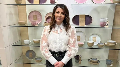 A young professional in a white lacy shirt smiling at work.