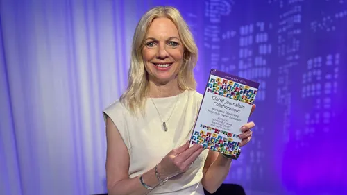 A woman with blonde hair wearing a white dress holds a book