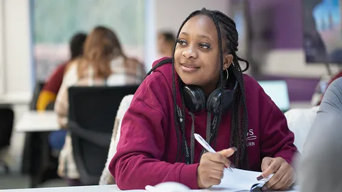A student in a burgundy hoodie paying attention in classroom.
