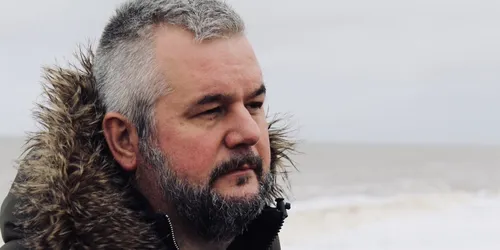 Man in black coat on beach