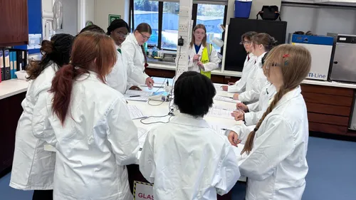 A group of female secondary school students in lab coats at the BASF Bradford site for a day of science activities.