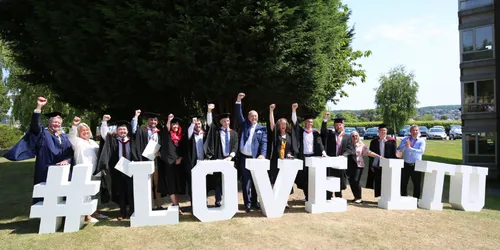 Graduates and lecturers stood by lettering in university grounds