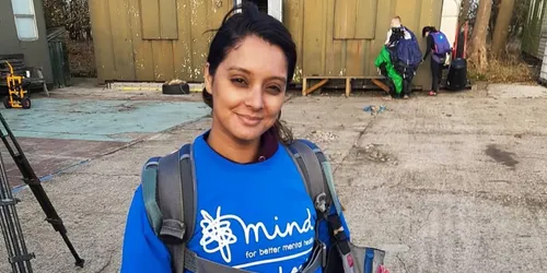 Woman with dark hair and backpack over her shoulders with blue Mind t-shirt on