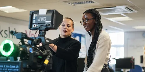 Two female journalism students setting up a camera and autocue