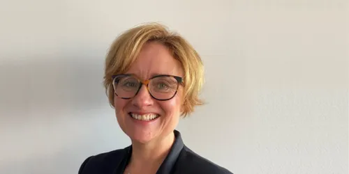 blonde woman with glasses and black suit jacket